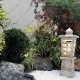 پاسیو سبز نسترن به سبک باغ ژاپنی فانوس سنگی شن تزئینی و پبل سفید a white stone lantern in a japanese garden style patio