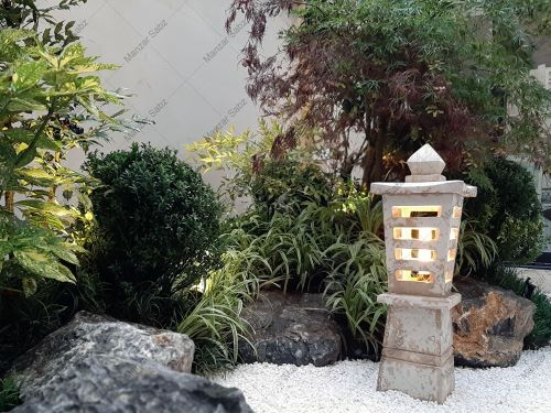 پاسیو سبز نسترن به سبک باغ ژاپنی فانوس سنگی شن تزئینی و پبل سفید a white stone lantern in a japanese garden style patio
